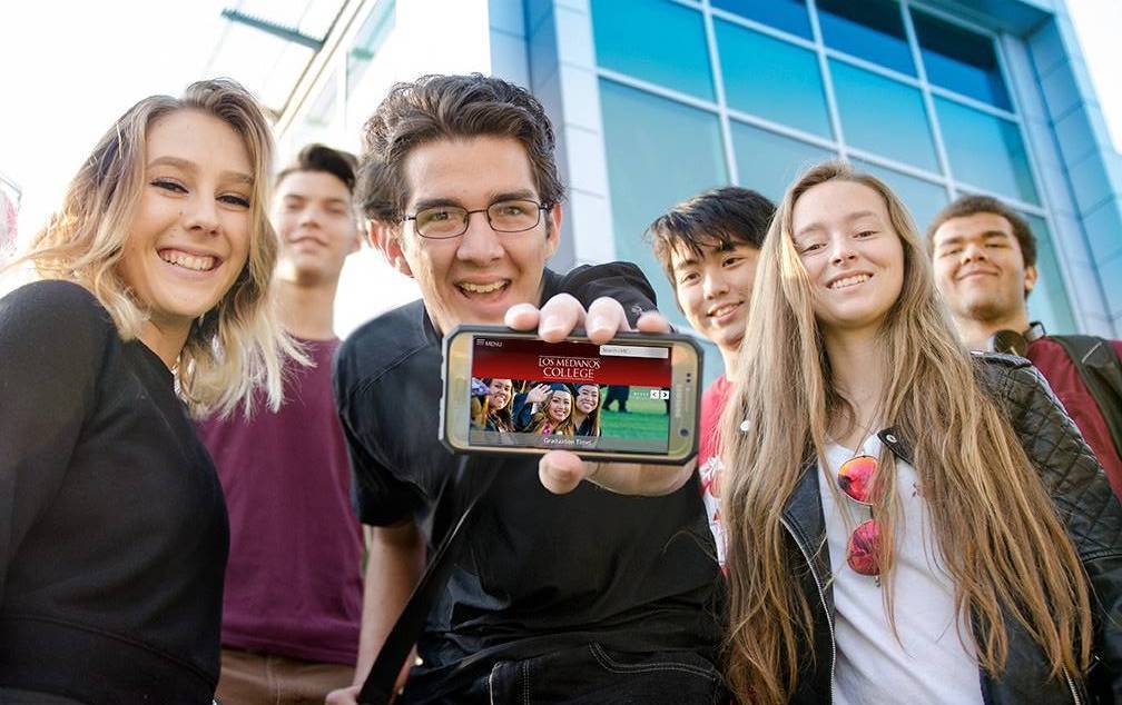 Students holding a smart phone showing the new respnsive website